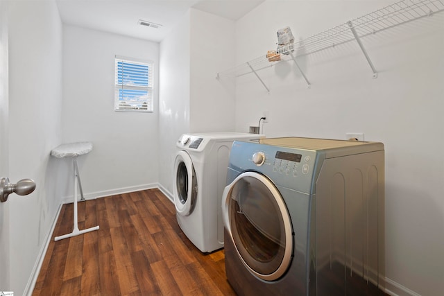 clothes washing area with dark hardwood / wood-style floors and washer and dryer