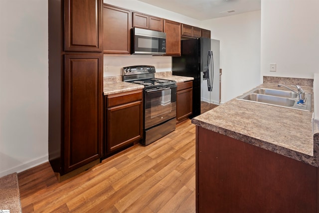 kitchen with light wood-type flooring, sink, and black appliances