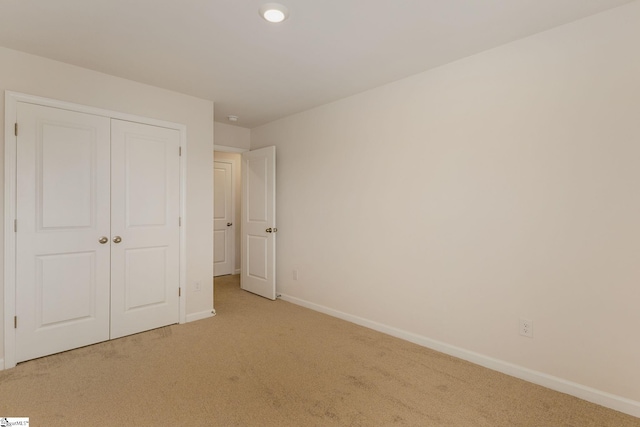 unfurnished bedroom with light carpet and a closet