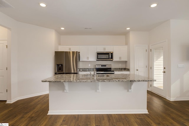 kitchen featuring stainless steel appliances, white cabinetry, dark wood-type flooring, and a kitchen island with sink