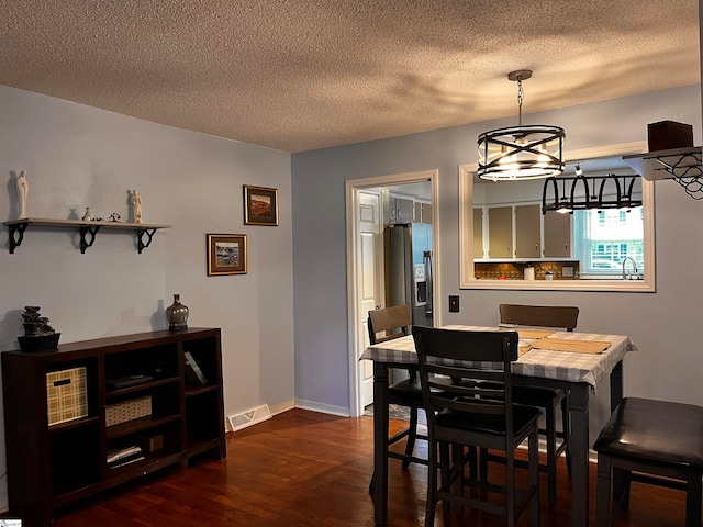 dining area with dark wood-type flooring, a chandelier, and a textured ceiling