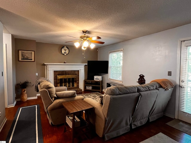 living room with a textured ceiling, a fireplace, dark hardwood / wood-style floors, and ceiling fan