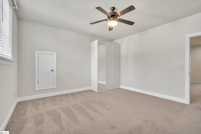 unfurnished bedroom featuring light carpet, ceiling fan, and a textured ceiling