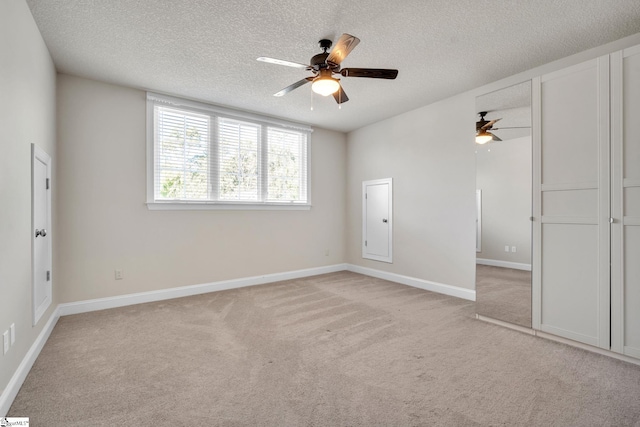 empty room featuring light carpet, ceiling fan, and a textured ceiling