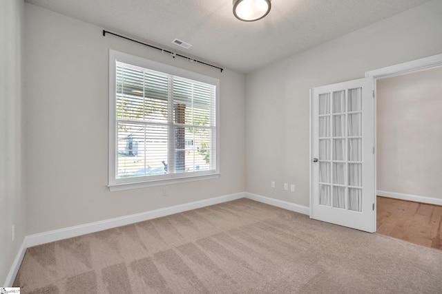 carpeted empty room featuring a textured ceiling