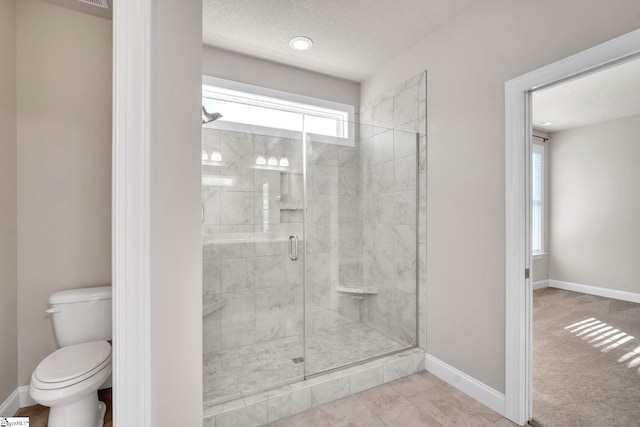 bathroom with a textured ceiling, a shower with shower door, toilet, and tile patterned floors