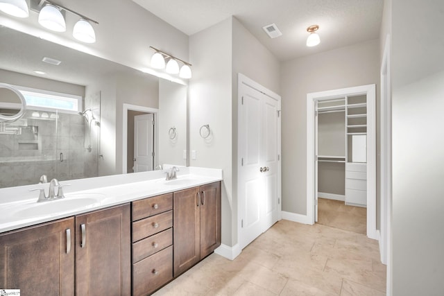 bathroom with a textured ceiling, vanity, and an enclosed shower