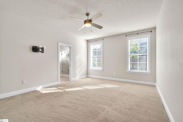 unfurnished bedroom featuring multiple windows, a textured ceiling, connected bathroom, and ceiling fan