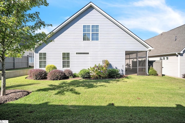 rear view of property with a lawn and a sunroom