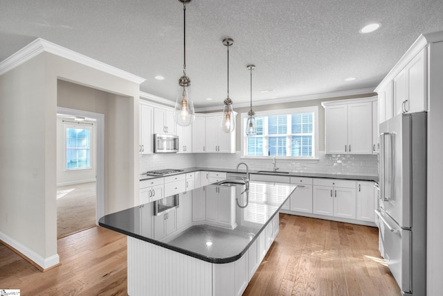 kitchen featuring white cabinets, an island with sink, appliances with stainless steel finishes, and light hardwood / wood-style floors