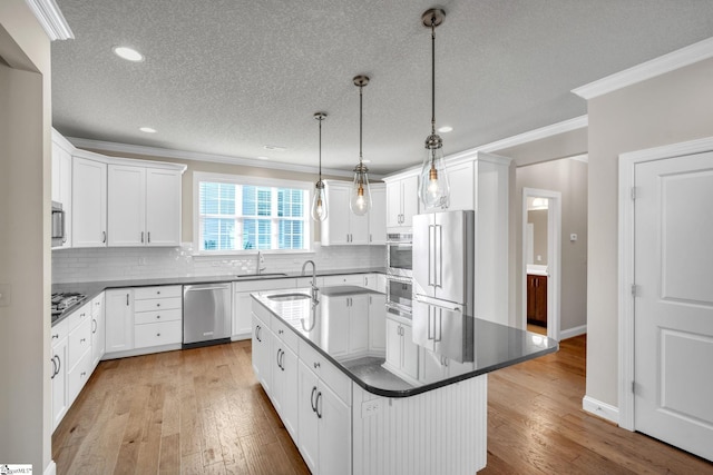 kitchen featuring appliances with stainless steel finishes, a center island with sink, light hardwood / wood-style flooring, and white cabinets