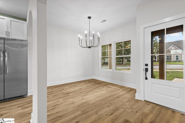 unfurnished dining area featuring light hardwood / wood-style floors and a chandelier