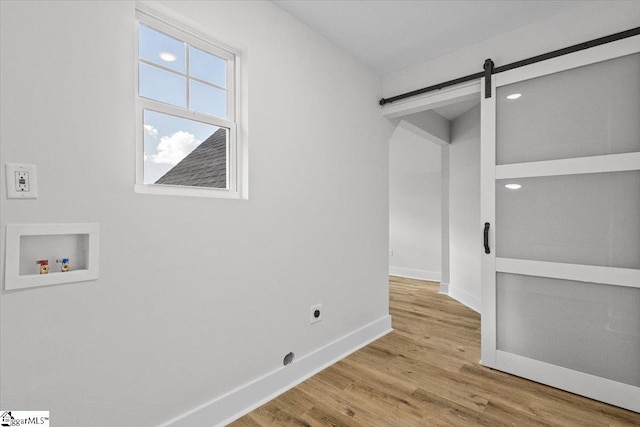 spare room featuring a barn door and light hardwood / wood-style flooring