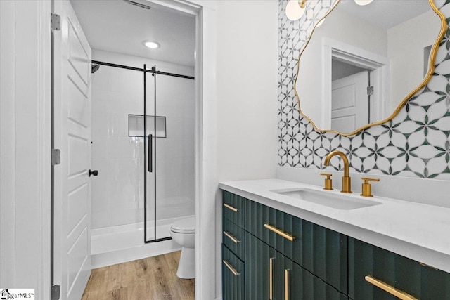 bathroom featuring wood-type flooring, walk in shower, vanity, and toilet