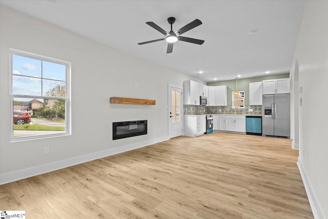 kitchen with light hardwood / wood-style flooring, white cabinets, appliances with stainless steel finishes, and plenty of natural light