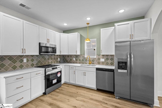 kitchen featuring light hardwood / wood-style floors, sink, white cabinetry, appliances with stainless steel finishes, and decorative light fixtures