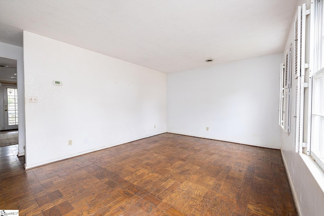 empty room with a textured ceiling and dark hardwood / wood-style flooring