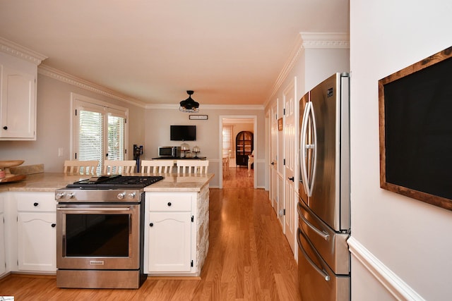 kitchen with appliances with stainless steel finishes, crown molding, light wood-type flooring, and white cabinets