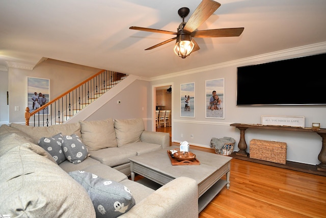 living room featuring ornamental molding, light hardwood / wood-style floors, and ceiling fan