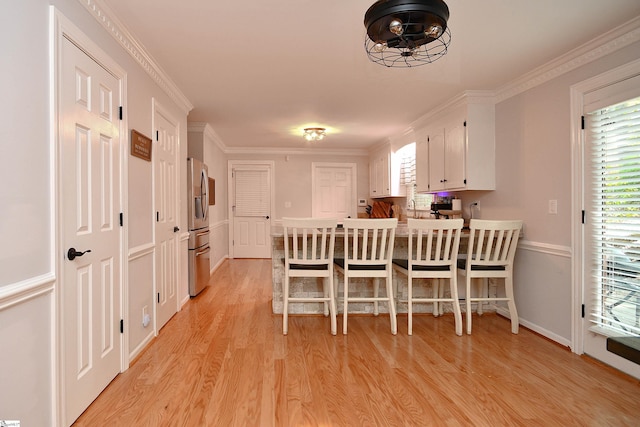 dining room featuring crown molding, sink, and light hardwood / wood-style flooring