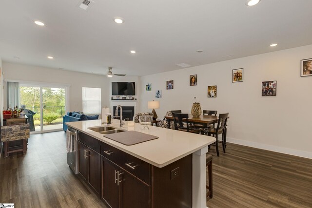 kitchen with dishwasher, dark wood-type flooring, a kitchen island with sink, sink, and ceiling fan