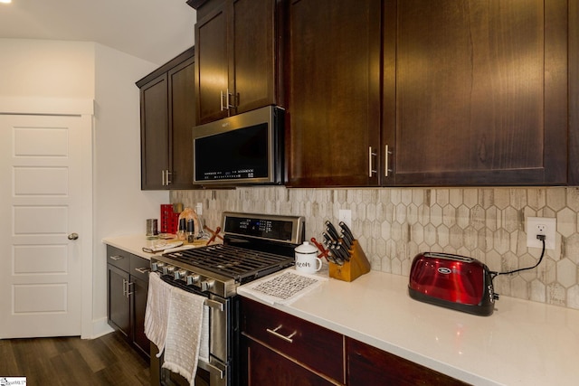 kitchen with dark brown cabinetry, stainless steel appliances, dark wood-type flooring, and tasteful backsplash