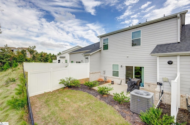 rear view of property with a lawn, central AC, and a patio area