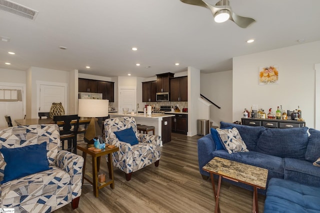 living room featuring ceiling fan, sink, and dark hardwood / wood-style flooring