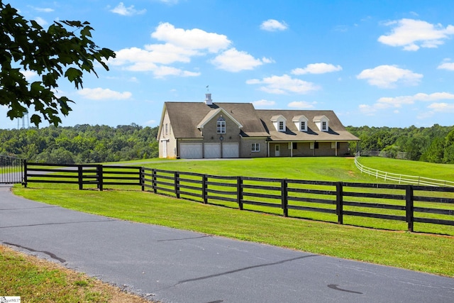 view of front of property with a garage, a rural view, and a front lawn