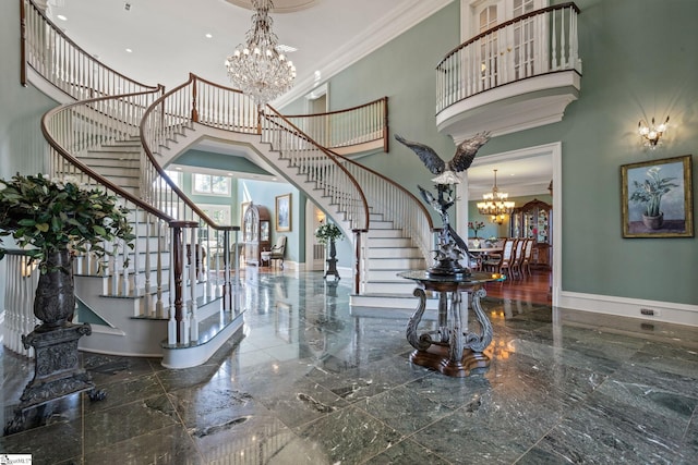 entryway featuring an inviting chandelier, a towering ceiling, and crown molding