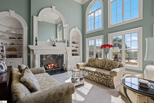 living room featuring carpet flooring, a high ceiling, a fireplace, and crown molding