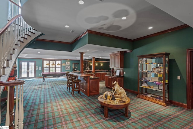 interior space featuring light colored carpet, indoor bar, ornamental molding, french doors, and ornate columns