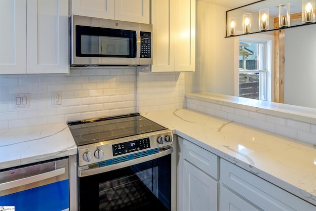 kitchen featuring white cabinets, hanging light fixtures, tasteful backsplash, stainless steel appliances, and light stone countertops