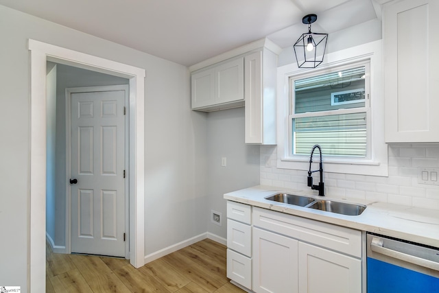 kitchen featuring dishwasher, hanging light fixtures, sink, and white cabinetry