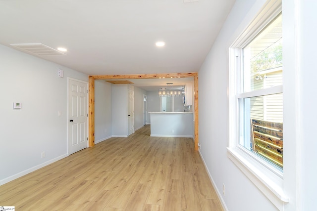 spare room with a notable chandelier and light wood-type flooring