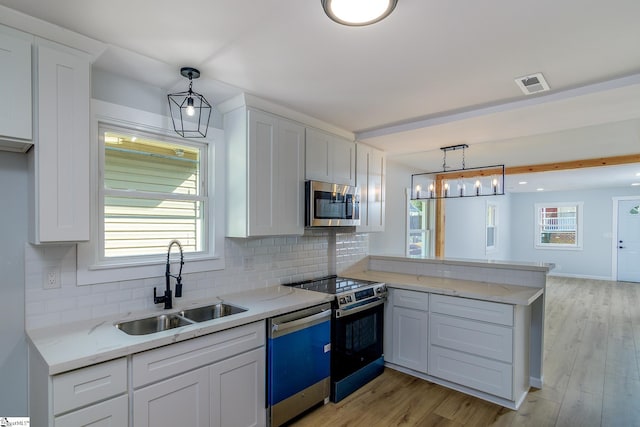 kitchen with white cabinets, stainless steel appliances, pendant lighting, and sink