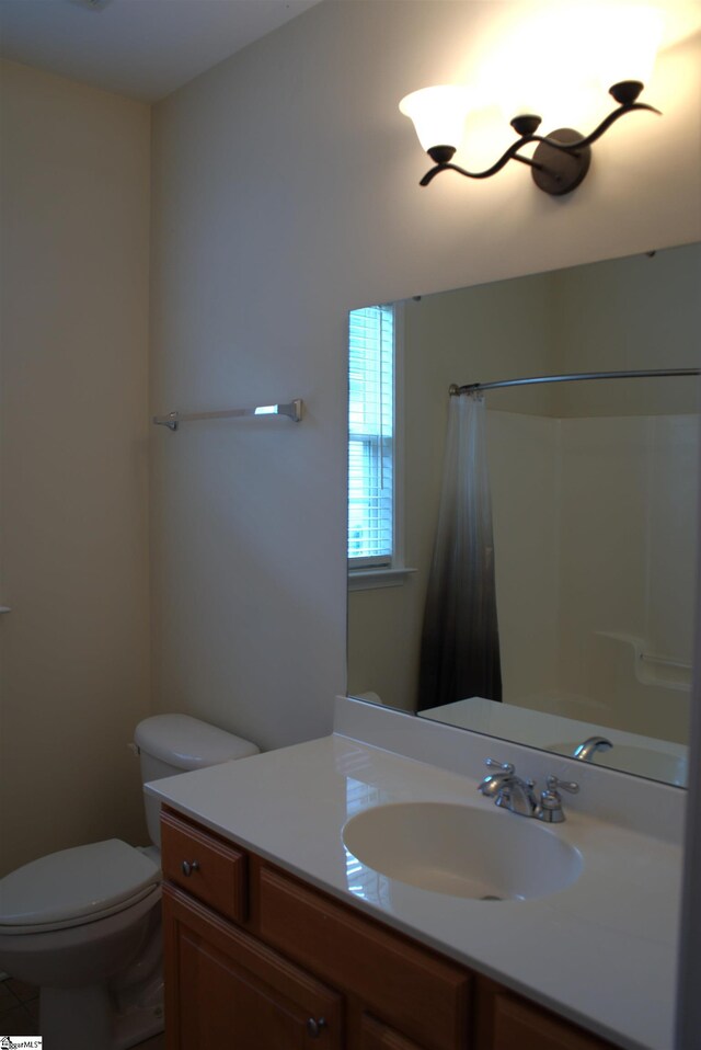 bathroom with walk in shower, vanity, and toilet