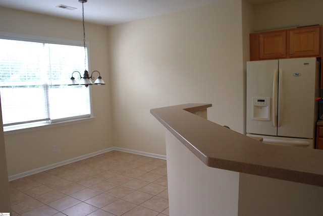 interior space with white refrigerator with ice dispenser, decorative light fixtures, and light tile patterned floors