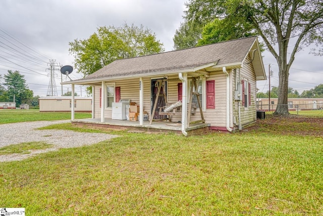 view of front facade featuring a porch, a front lawn, and central AC unit