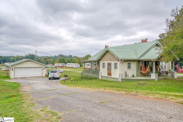 view of front of house with covered porch, an outdoor structure, a front yard, and a garage