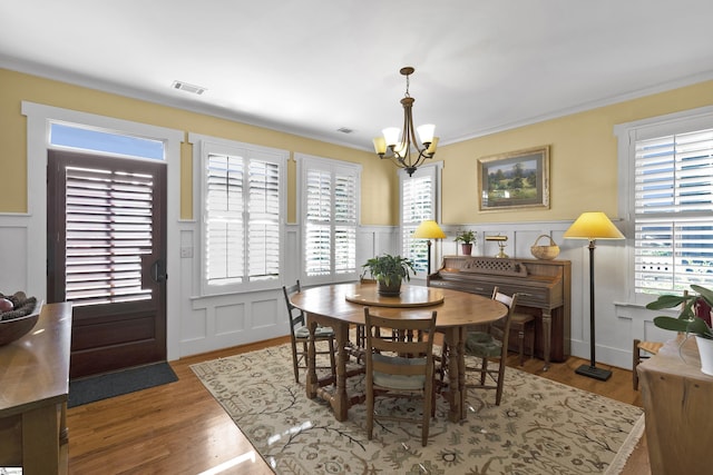 dining space with dark wood-type flooring, ornamental molding, and a chandelier