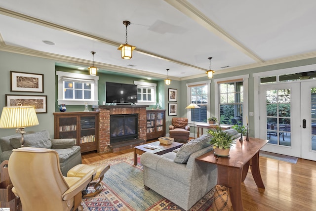 living room featuring ornamental molding, light hardwood / wood-style flooring, a fireplace, and french doors