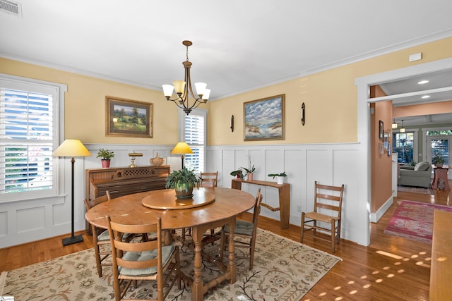 dining room with wood-type flooring, crown molding, and an inviting chandelier