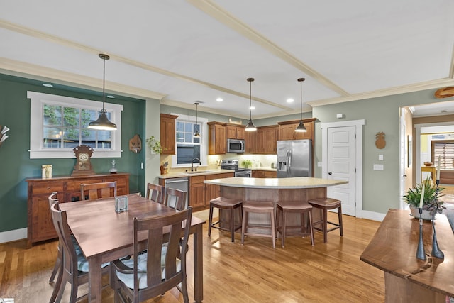 dining space with ornamental molding, sink, and light hardwood / wood-style flooring