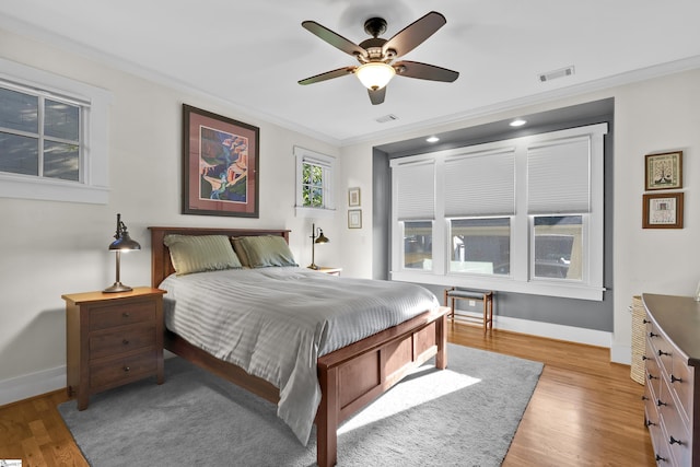 bedroom with ornamental molding, ceiling fan, and light hardwood / wood-style floors