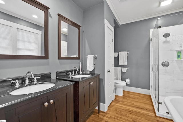 full bathroom with plus walk in shower, wood-type flooring, vanity, toilet, and crown molding