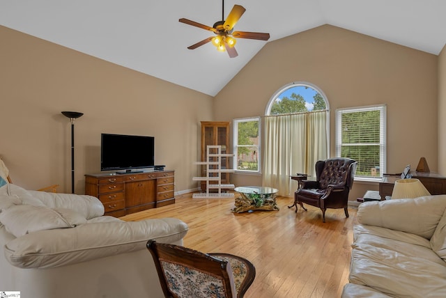 living area with high vaulted ceiling, baseboards, a ceiling fan, and light wood-style flooring
