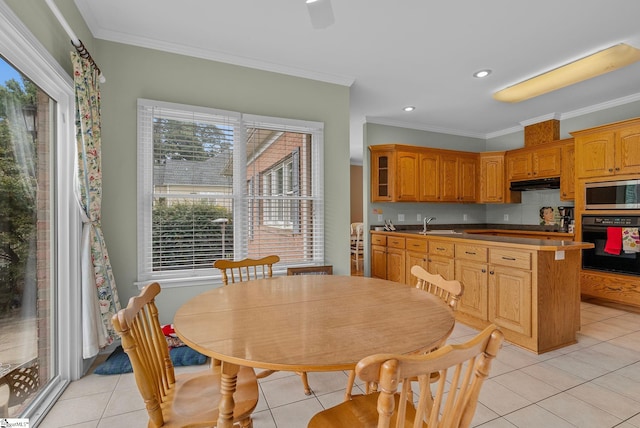 kitchen with crown molding, stainless steel microwave, under cabinet range hood, and oven