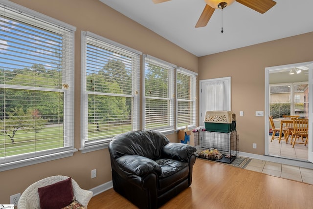 living area featuring baseboards, a ceiling fan, and wood finished floors