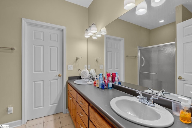 bathroom with double vanity, a shower stall, a sink, and tile patterned flooring